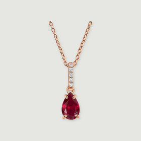 A rose gold chain and polished prongs frame a red pear-shaped pendant beneath five round white stones.