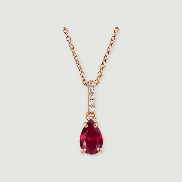 A rose gold chain and polished prongs frame a red pear-shaped pendant beneath five round white stones.