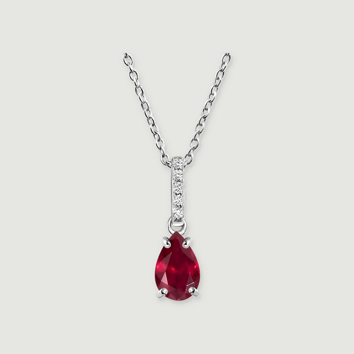 A silver necklace holds a faceted red pear-shaped stone with a vertical row of five white accents on its bail.