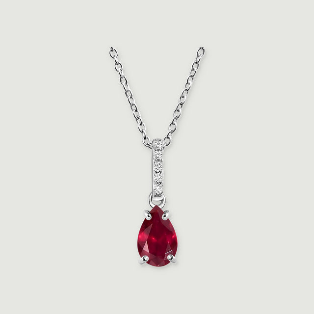 A silver necklace holds a faceted red pear-shaped stone with a vertical row of five white accents on its bail.