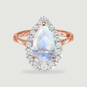 A pear-shaped moonstone is surrounded by round diamonds on a polished rose gold ring against a light gray background.