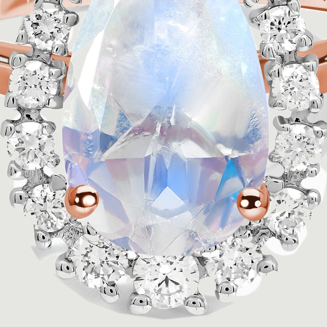 The lower moonstone facets, two rose gold prongs and surrounding round diamonds are shown in detail.
