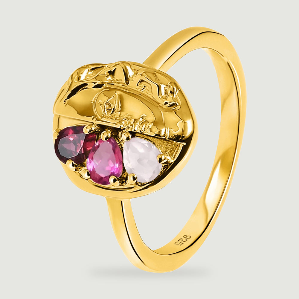 An angled yellow gold ring reveals its curved band and three pear-shaped stones beneath the sculpted face.