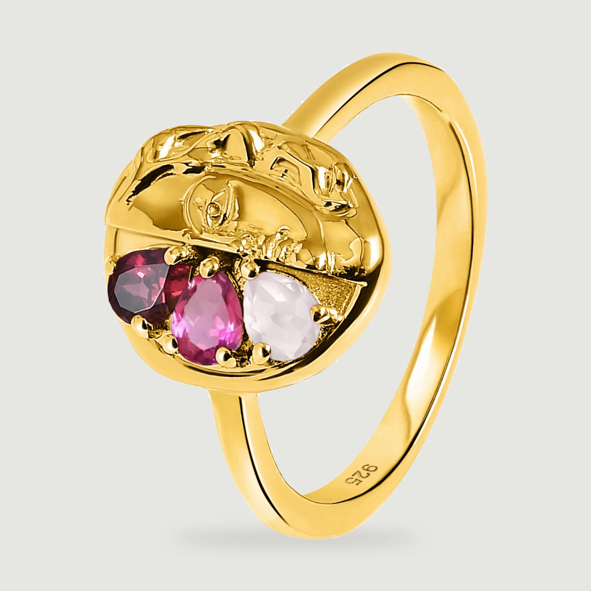 An angled yellow gold ring reveals its curved band and three pear-shaped stones beneath the sculpted face.