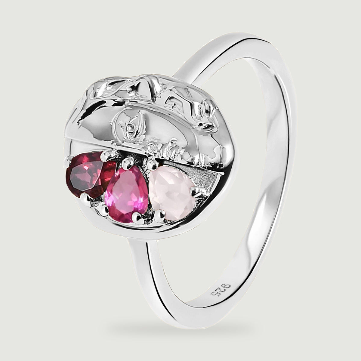 The silver ring is shown at an angle with its curved band, polished face relief and three colored stones visible.