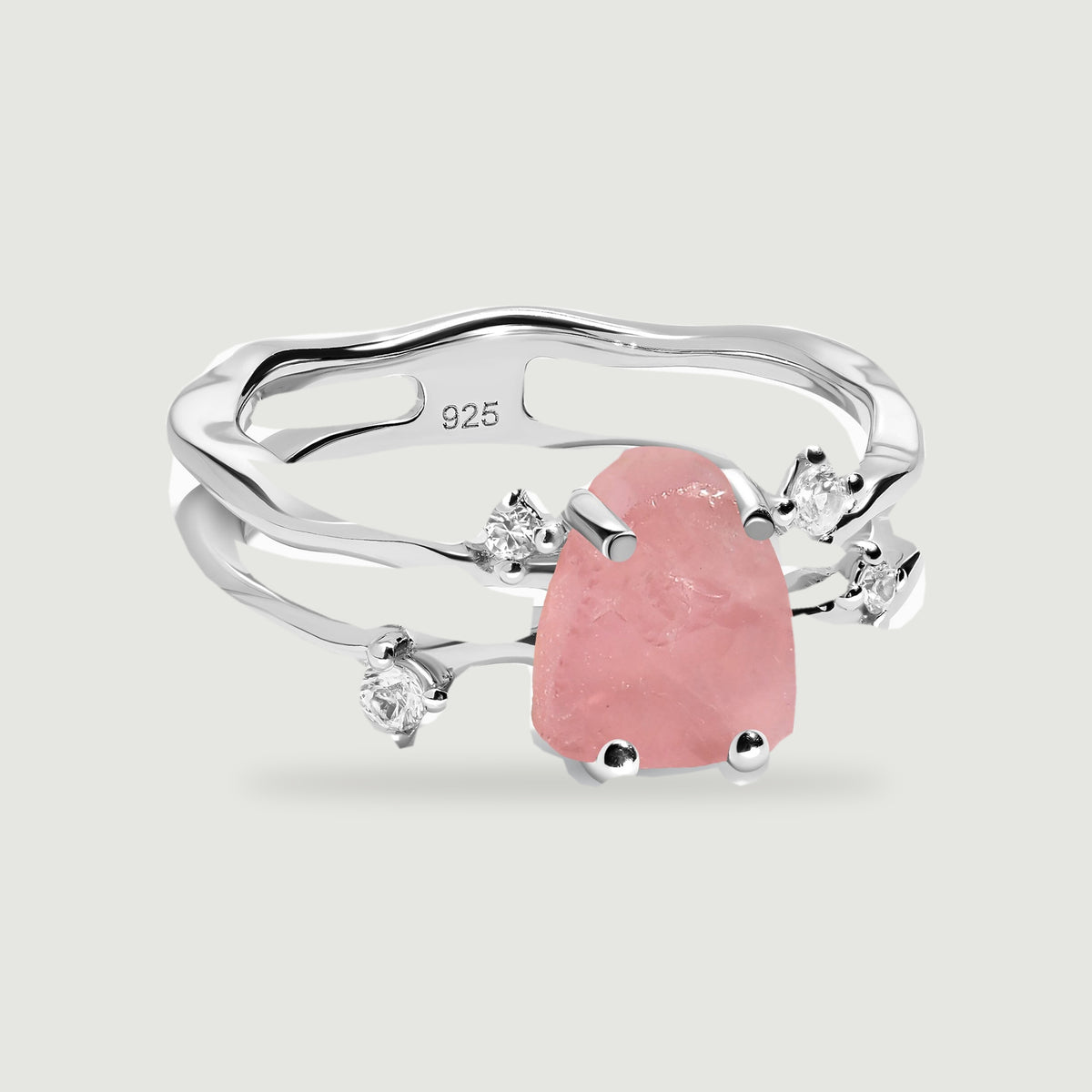 A sterling silver ring displays a pink rose quartz center, four clear accents, and an open double band against pale gray.