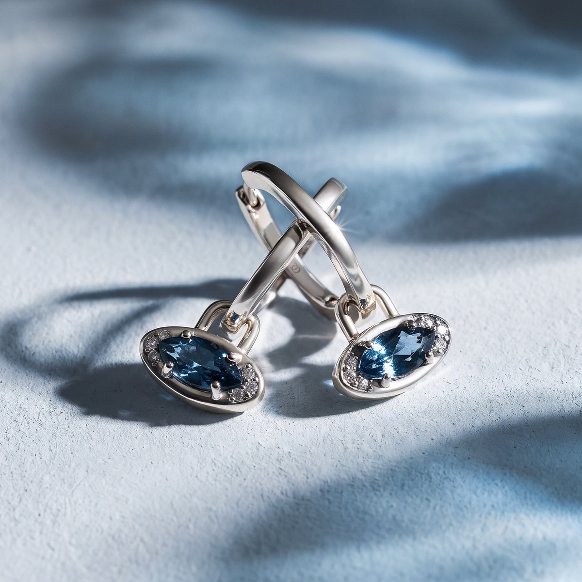 Pair of evil eye hoop charms on a blue background