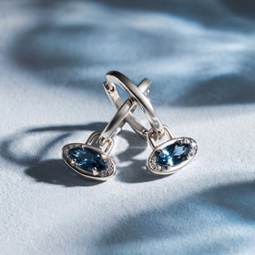 Pair of evil eye hoop charms on a blue background