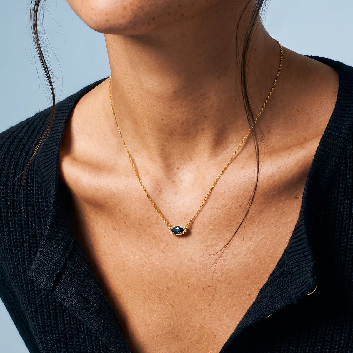 Model wearing the blue topaz eye motif pendant over a black top
