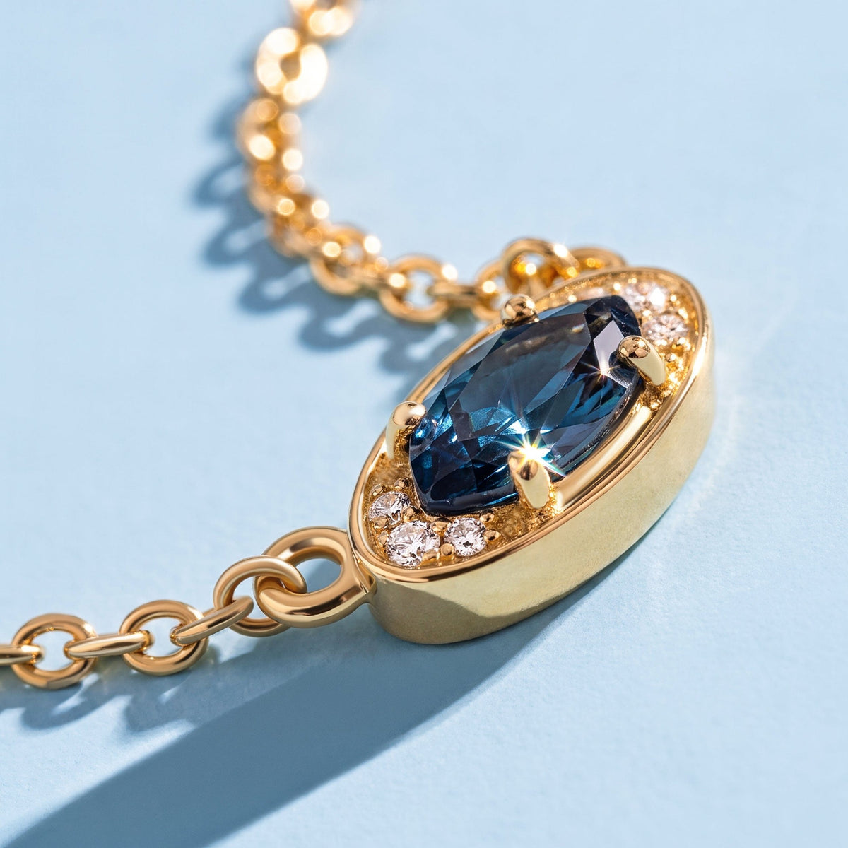Blue topaz pendant on a chain against a blue background