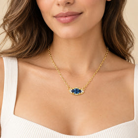 Blue topaz evil eye pendant draped over a white top in soft light