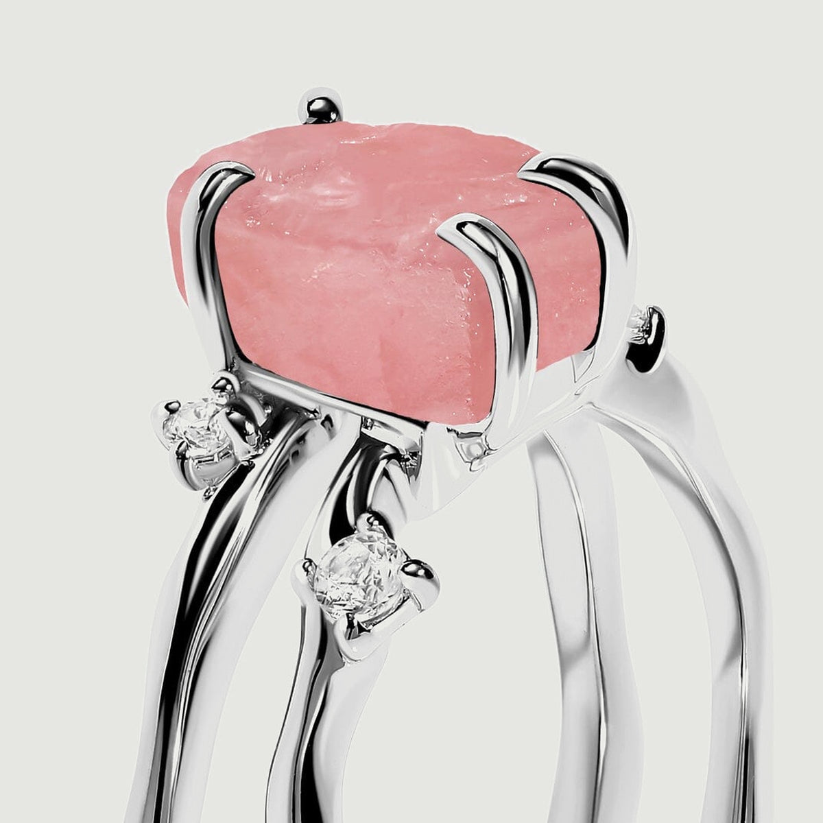 White gold prongs hold a pink crystal above the split band, with two clear accent stones visible from the side.