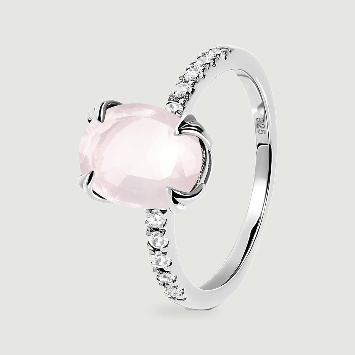 An upright sterling silver ring reveals its oval pink stone, curved band and open setting from an angled view.