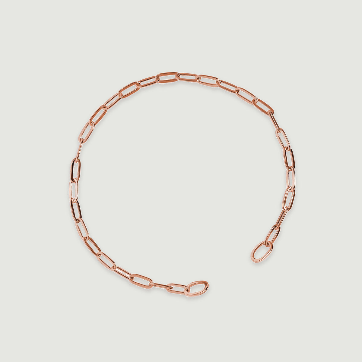 The rose gold bracelet lies diagonally with two rounded end loops visible.