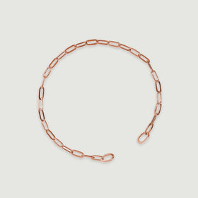 The rose gold bracelet lies diagonally with two rounded end loops visible.