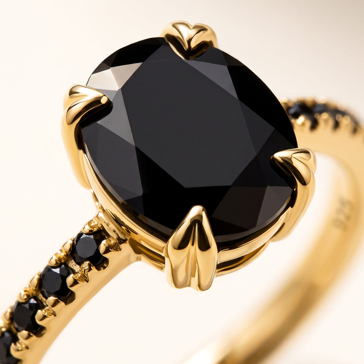 A close view of the black oval stone reveals angular facets, yellow gold prongs, and round black stones along the band.