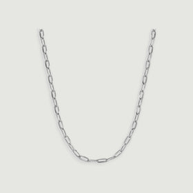 A silver chain necklace displays narrow reflective links arranged in a centered curve on light gray.