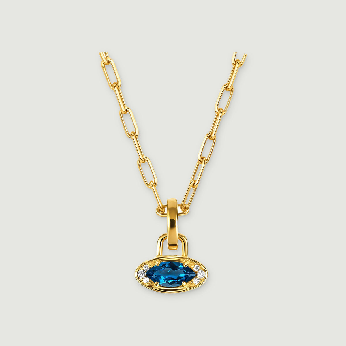 A yellow gold-tone chain supports a blue oval pendant with small clear stones on either side.