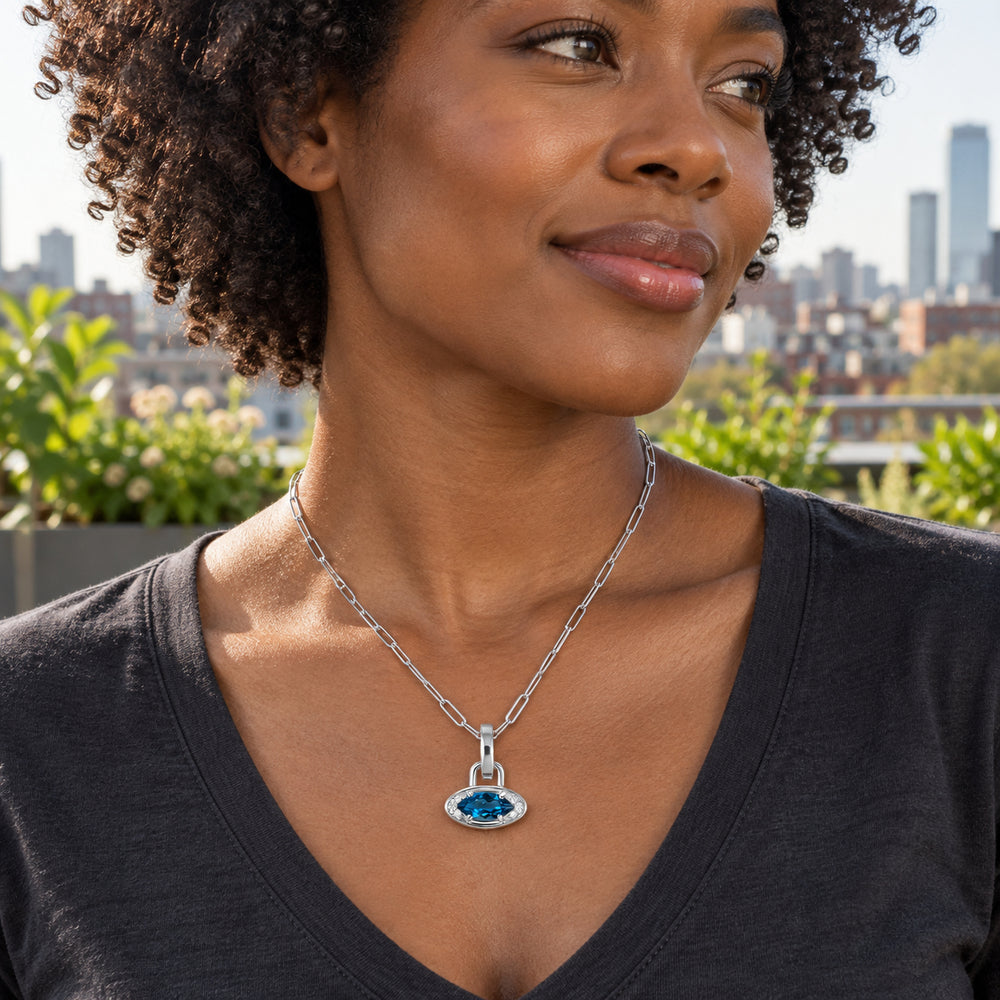 A woman in a charcoal V-neck shirt wears the silver-tone blue pendant necklace in a rooftop garden.