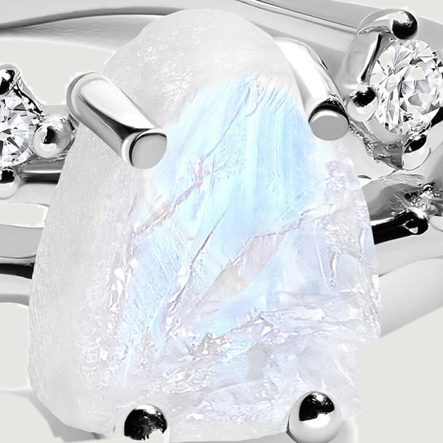 A close view shows the uneven moonstone surface between polished silver prongs.