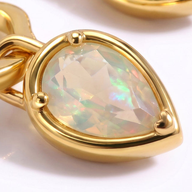 A close view shows a faceted pear-shaped opal held by three yellow gold prongs and a polished rim.