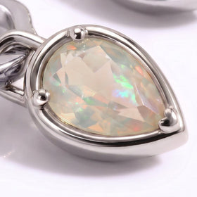 A faceted opal reflects green and peach colors inside a silver-tone three-prong setting.