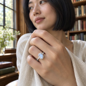 A woman with a black bob wears the white gold moonstone ring beside a library window.