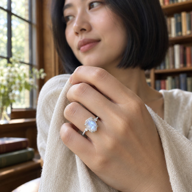 A woman with a black bob wears the white gold moonstone ring beside a library window.