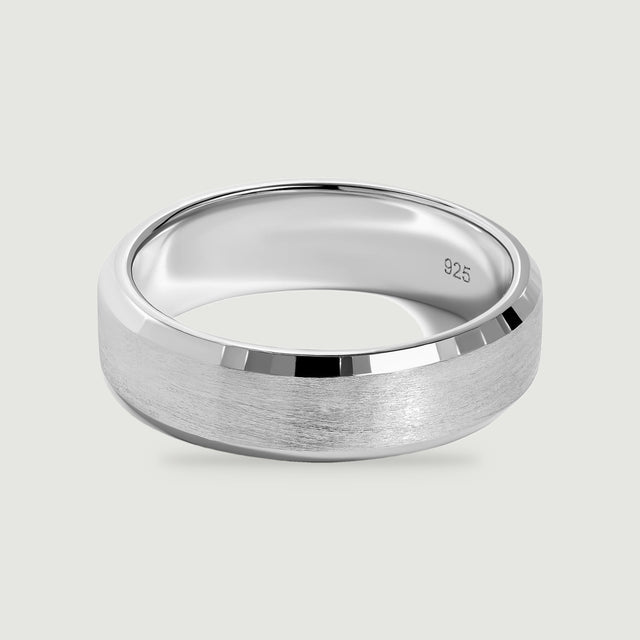 A sterling silver band displays a brushed center and polished beveled edges on a light gray surface.