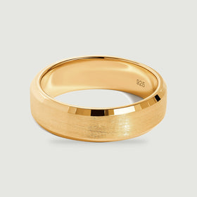 A yellow gold vermeil ring rests at an angle with its smooth interior and satin exterior visible.