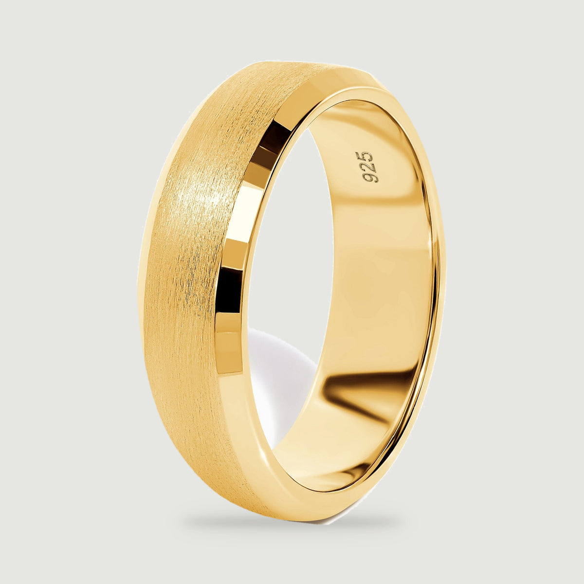 A yellow gold vermeil band stands on its edge, revealing the polished inside and textured outer surface.