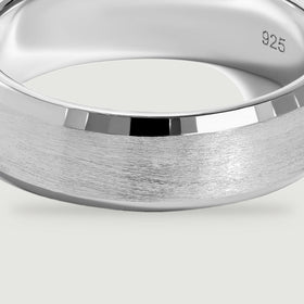 A close view of the silver ring reveals fine horizontal brush marks beneath a bright polished bevel.
