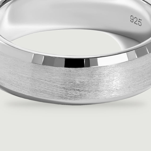 A close view of the silver ring reveals fine horizontal brush marks beneath a bright polished bevel.