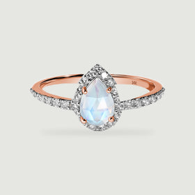 A rose gold band holds a pale pear-shaped moonstone surrounded by a bright diamond halo.