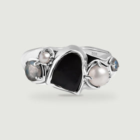 A sterling silver ring with a black center stone, two white pearls, and two blue-gray side stones on a light gray background.