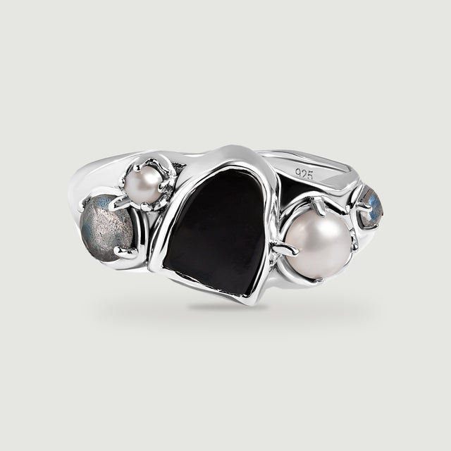 A sterling silver ring with a black center stone, two white pearls, and two blue-gray side stones on a light gray background.