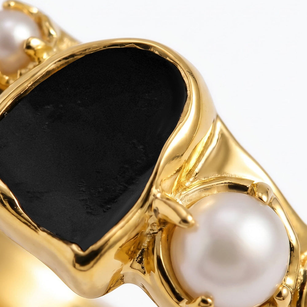 Close-up of the black stone and larger white pearl in the yellow gold setting.
