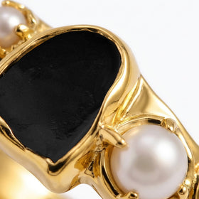 Close-up of the black stone and larger white pearl in the yellow gold setting.