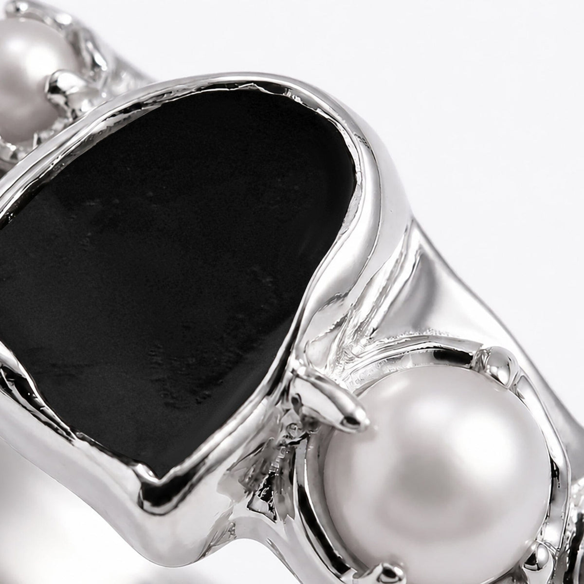 Close-up of the black stone and larger white pearl in the silver setting.