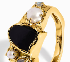 Angled view of the black stone, pearl prongs, and upper yellow gold ring band.