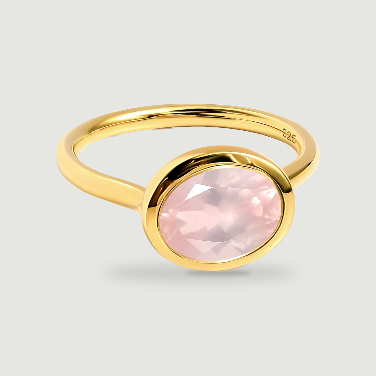 A yellow gold ring displays a faceted blush pink stone and a smooth rounded band.