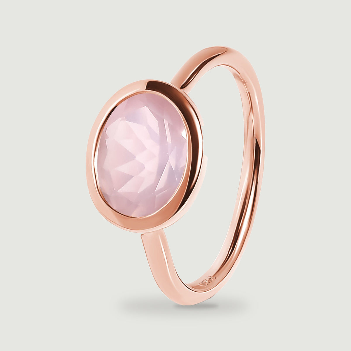 A tilted rose gold ring reveals the raised oval pink stone and its curved band.