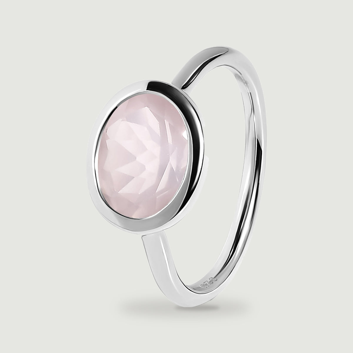 A silver ring stands at an angle with a pale pink stone in a low oval bezel.