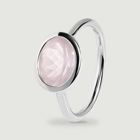 A silver ring stands at an angle with a pale pink stone in a low oval bezel.