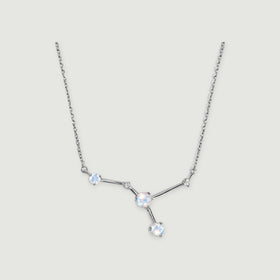 A silver necklace displays three round moonstones and two smaller clear stones joined by polished bars on a light grey background.