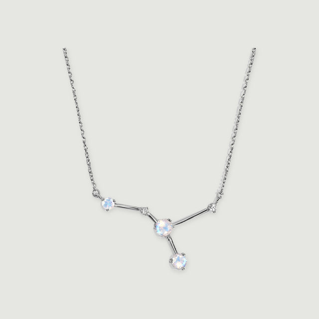 A silver necklace displays three round moonstones and two smaller clear stones joined by polished bars on a light grey background.