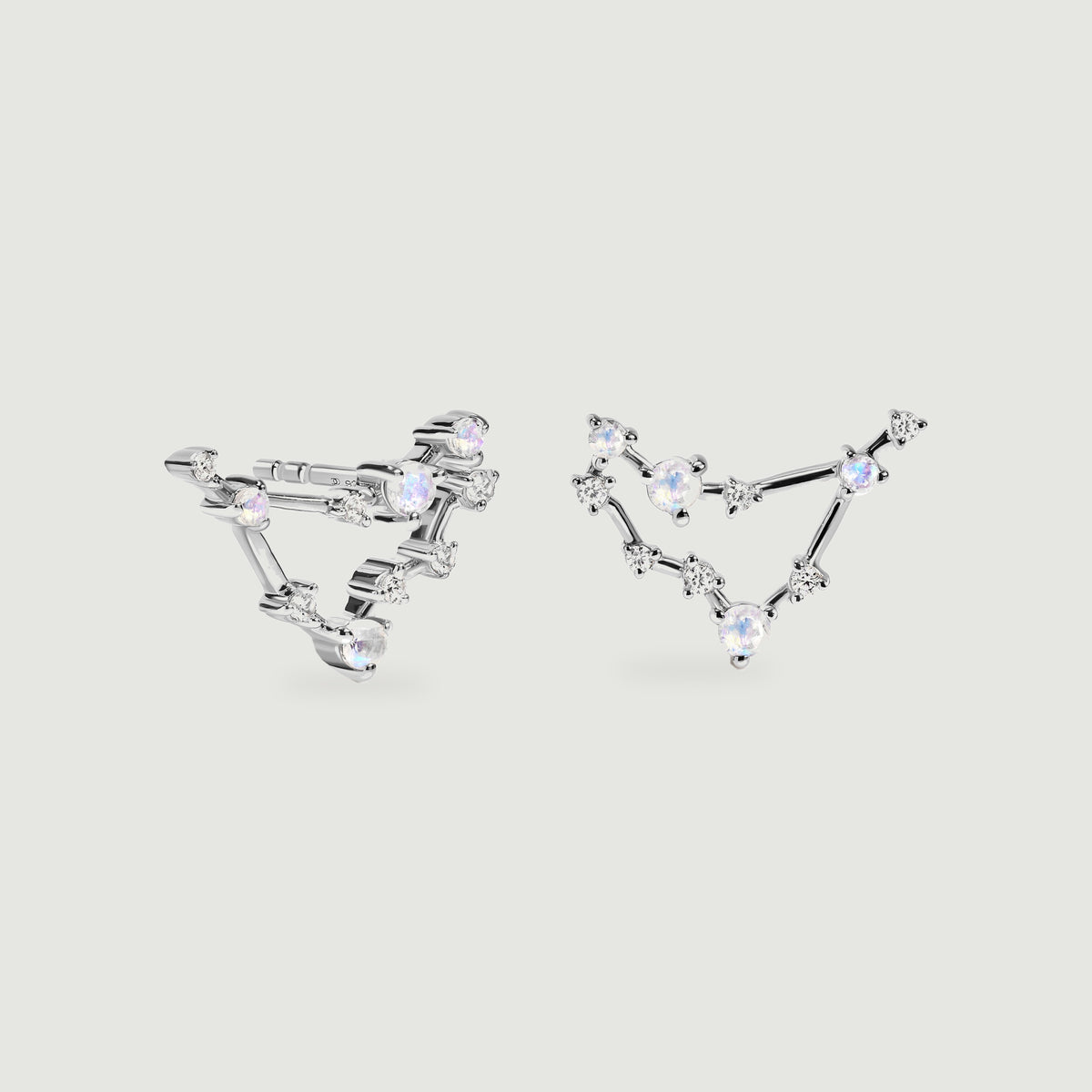 Silver constellation earrings rest side by side with iridescent round stones and polished connecting bars.