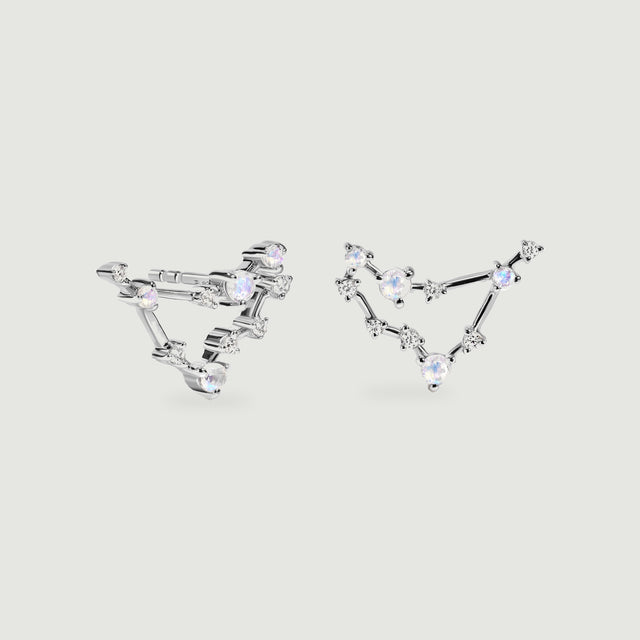 Silver constellation earrings rest side by side with iridescent round stones and polished connecting bars.