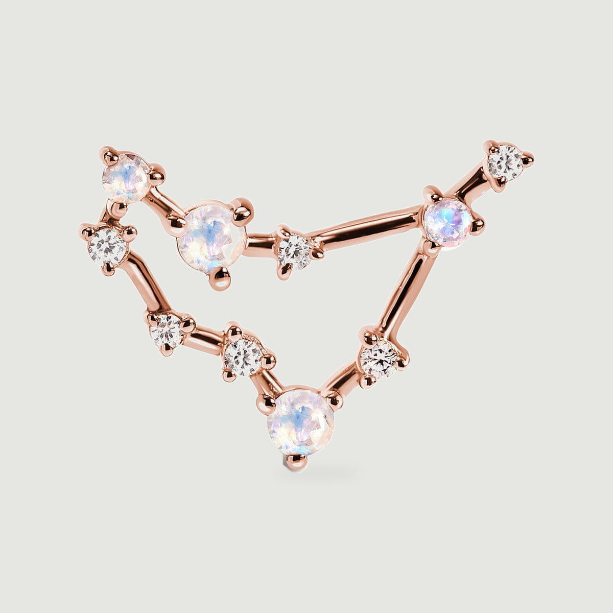 A close view of the rose gold stud shows its angular frame, rounded prongs, and pale stones with blue and pink reflections.