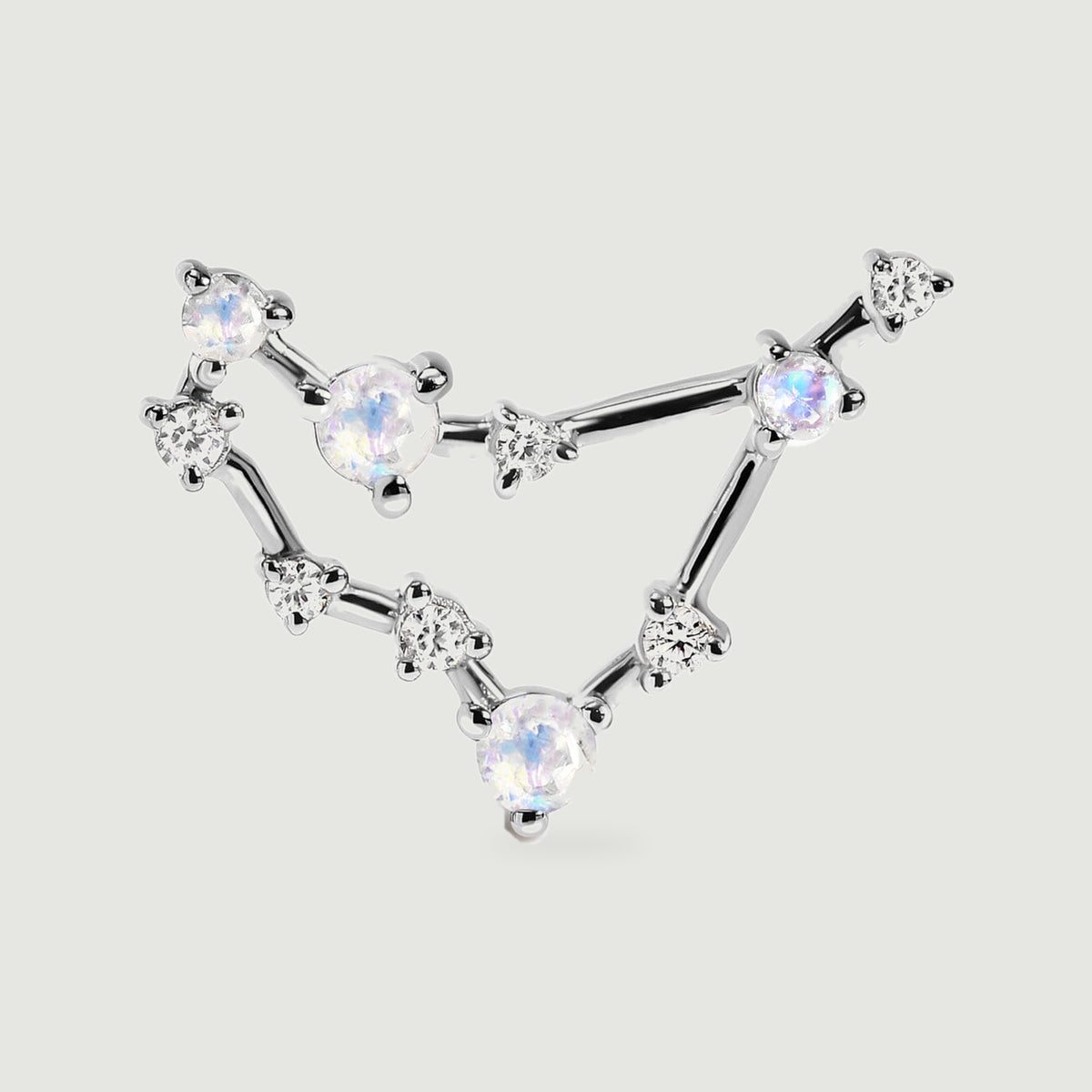 A silver stud is pictured close up, revealing the polished bars and small prong settings around its pale gemstones.